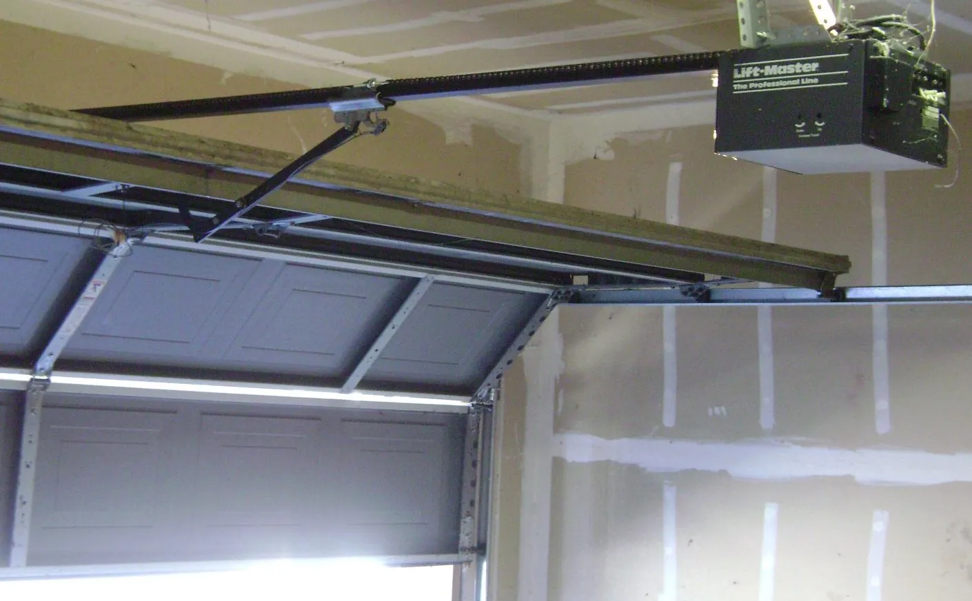 Chain drive garage door opener with rail mounted above a closed door